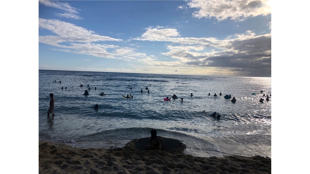 In this photo taken May 13, 2020 in Honolulu, people are in the water at a Waikiki beach. A group of people are helping track down violators of a 14-day quarantine on travelers arriving to Hawaii. (AP Photo/Jennifer Sinco Kelleher)