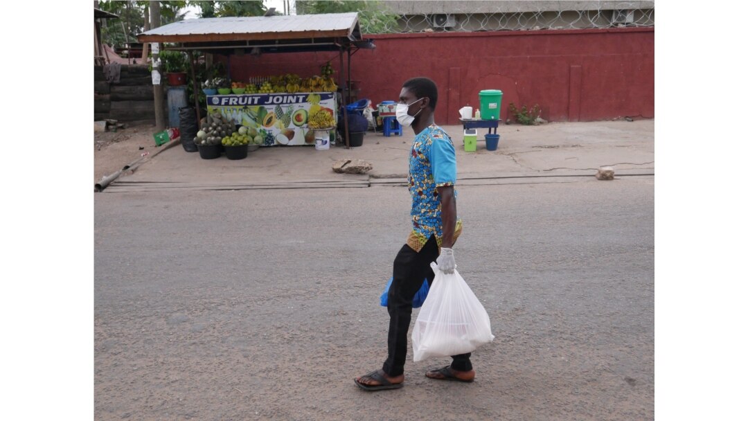 Oliver Tetteh carries packages of staple foods to distribute to households in Ghana's capital Accra, a city which has been in a partial lockdown since March 30, with many people out of work. (Stacey Knott/VOA)