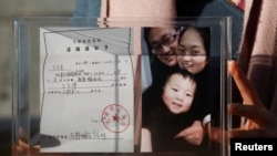 人權律師王全璋的妻子李文足2018年12月17日向媒體展示逮捕令和家庭照。（路透社）
