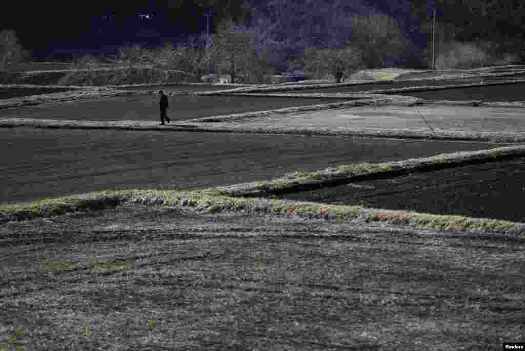 A man walks between fallow rice fields in Miyakoji in Tamura, Fukushima prefecture, April 1, 2014.