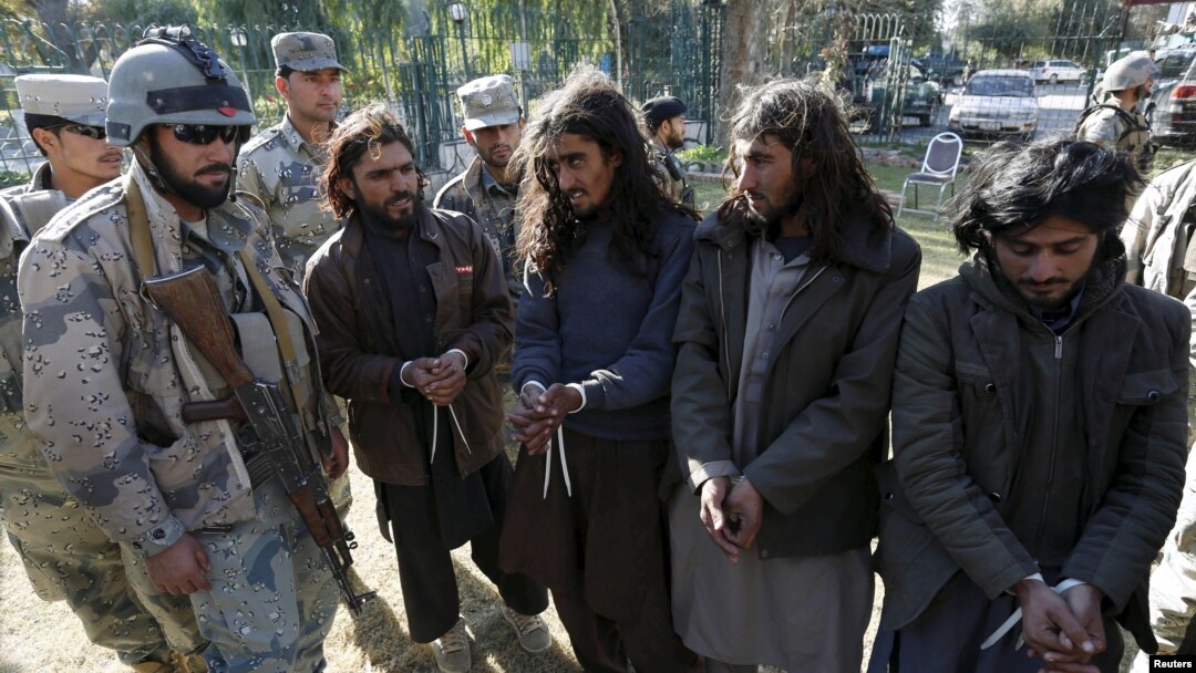 Taliban militants, right, who were arrested by Afghan border police, stand during a presentation of seized weapons and equipment, Jalalabad, Dec. 29, 2015.