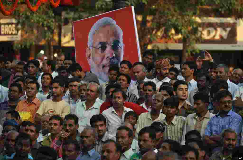 Indians gather to watch the swearing in ceremony of their new prime minister Narendra Modi on a large television by a street corner, New Delhi, May 26, 2014.