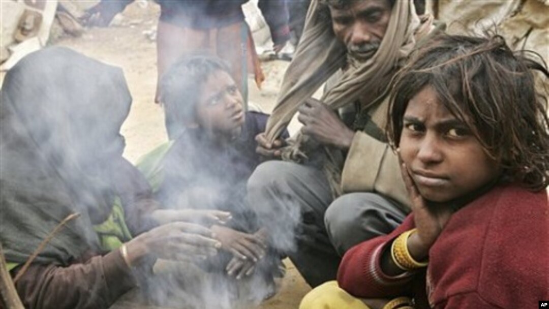 A family of workers sits near a kitchen fire at a makeshift shelter near a construction site, in Gurgaon, India, (file photo)