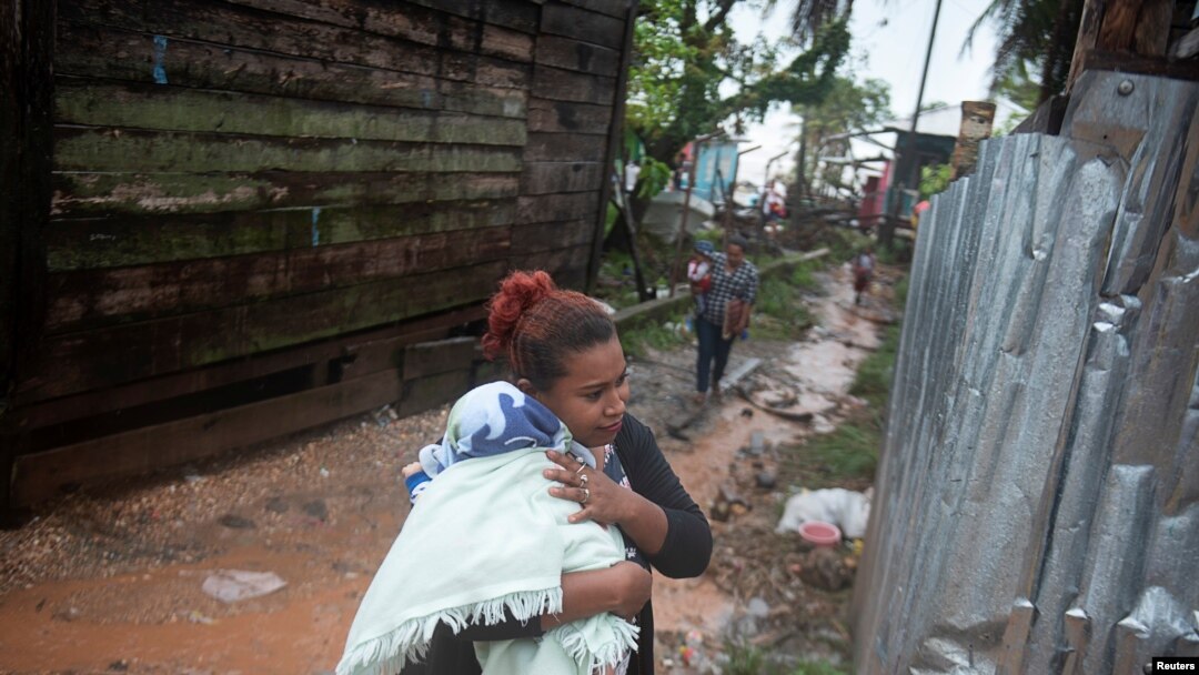 Una mujer protege a su bebé de la lluvia cuando el huracán Iota se acercaba a Puerto Cabezas, Nicaragua, 16 de noviembre de 2020.