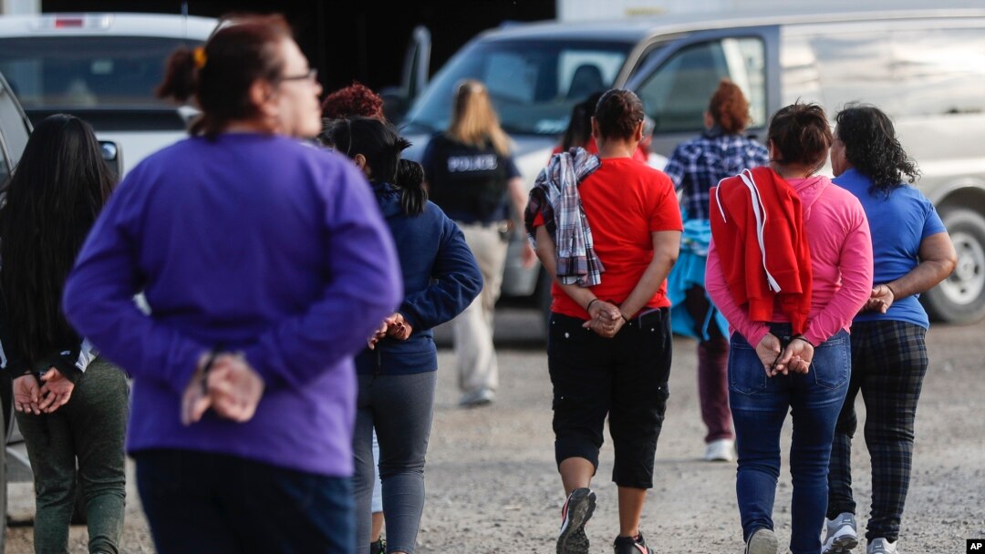 Government agents lead suspects in custody toward a restroom during an immigration sting at Corso's Flower and Garden Center in Castalia, Ohio, June 5, 2018.