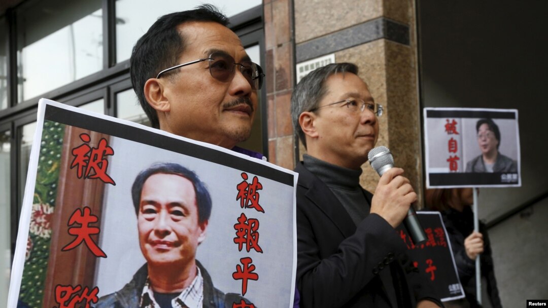 FILE - Pro-democracy Civic Party protesters carry portraits of missing booksellers Lee Bo, left, and Gui Minhai outside the Chinese Liaison Office in Hong Kong, Jan. 19, 2016.