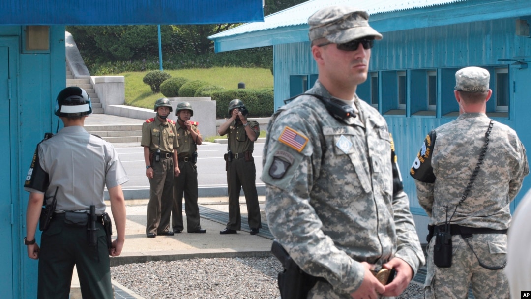 FILE - In this July 27, 2014, file photo, North Korean army soldiers watch the south side while South Korean, left, and U.S. Army soldiers stand guard at the truce villages of Panmunjom in Paju, South Korea. 