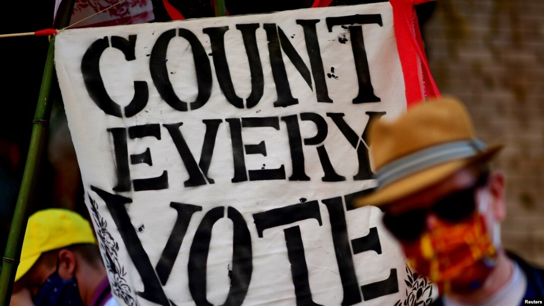 Un manifestante en Filadelfia, Pensilvania, levanta un cartel indicando que "cada voto cuenta" mientras funcionarios siguen con el escrutinio de boletas.