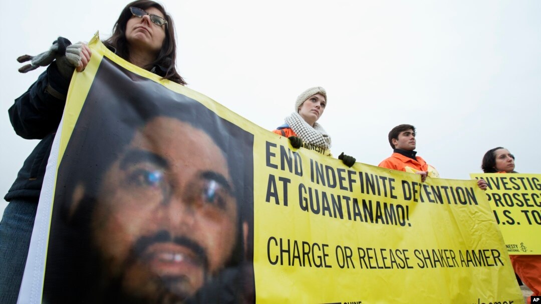 FILE - Human rights activists hold a banner with a picture of Saudi national Guantanamo detainee Shaker Aamer during a rally near the White House in Washington, Jan. 11, 2013.