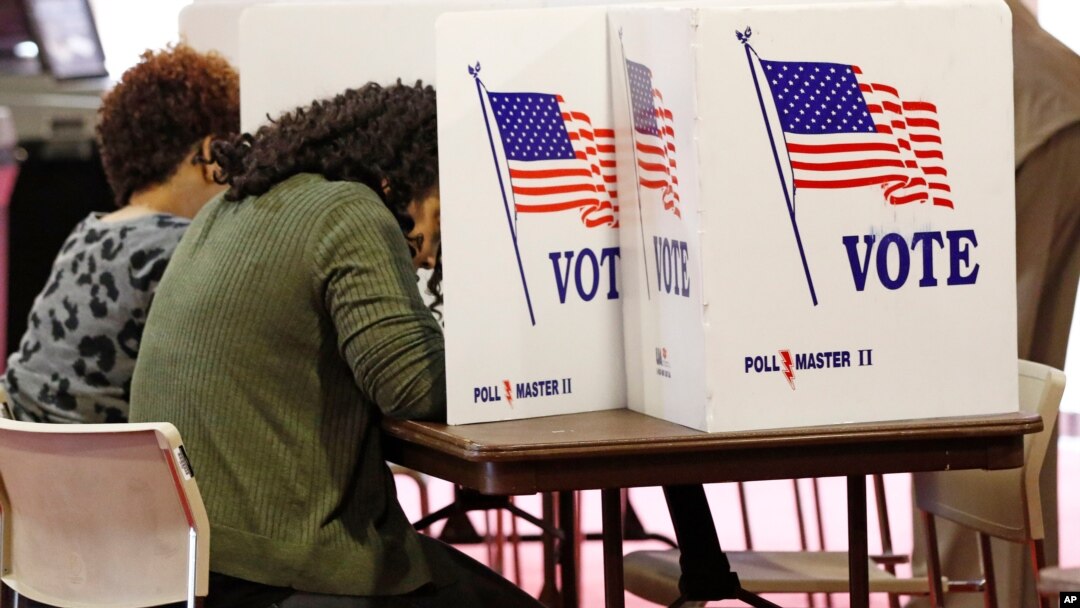 FILE - Voters work on their ballots in the kiosks in Jackson, Miss., March 10, 2020.
