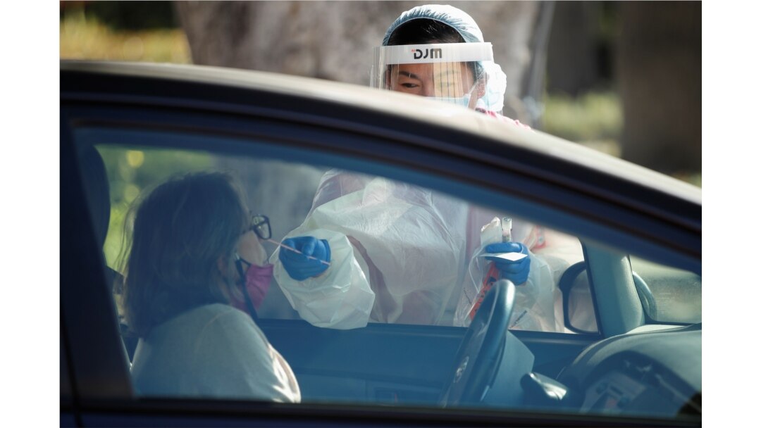 A health care worker at LAC USC Medical Center swabs a person at a drive-through testing center during the coronavirus outbreak, in Los Angeles, California, Dec. 10, 2020.