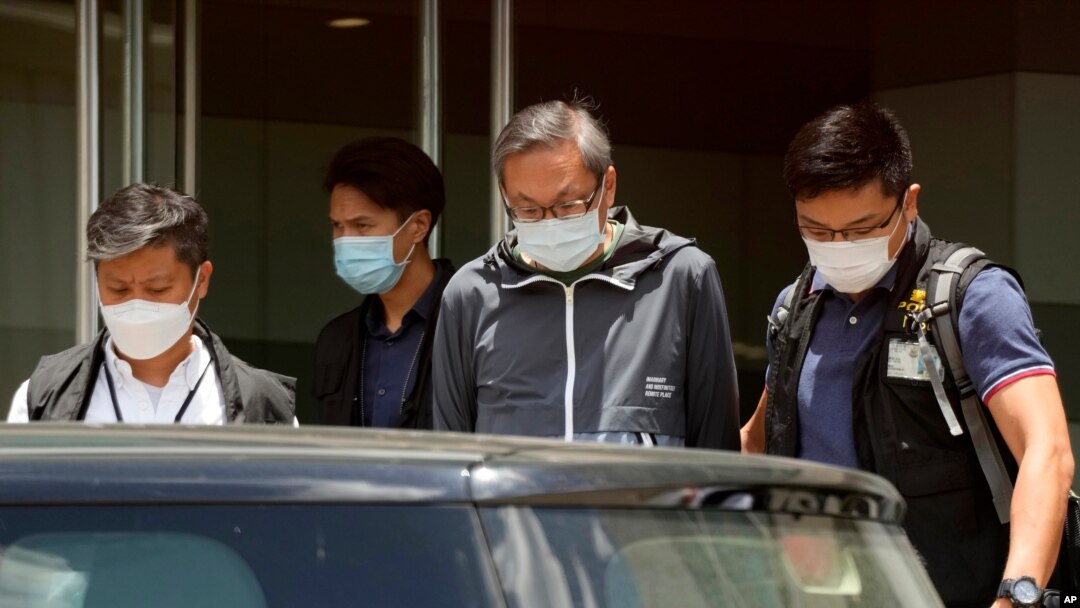 Police officers escort Cheung Kim-hung, right, CEO and executive director of Next Digital Ltd at Apple Daily headquarters in Hong Kong, June 17, 2021. 