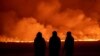 La gente observa cómo el cielo nocturno se ilumina debido a la erupción de un volcán en Grindavik, en la península de Reykjanes, Islandia, el lunes 18 de diciembre de 2023.