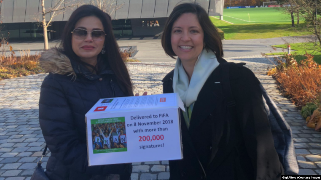 Women’s rights activists Maryam Qashqaei Shojaei and Gigi Alford hold a petition outside FIFA’s Zurich headquarters, Nov. 8, 2018. The petition calls for an end to Iran’s decades-old ban on Iranian women buying stadium tickets for men’s sporting events.