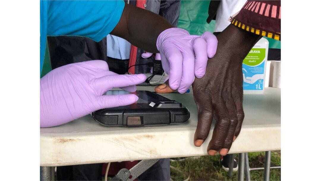 A woman's fingerprints are scanned before receiving a cash voucher at the Lobule refugee settlement in Uganda. August 14, 2019 (T. Krug/VOA)