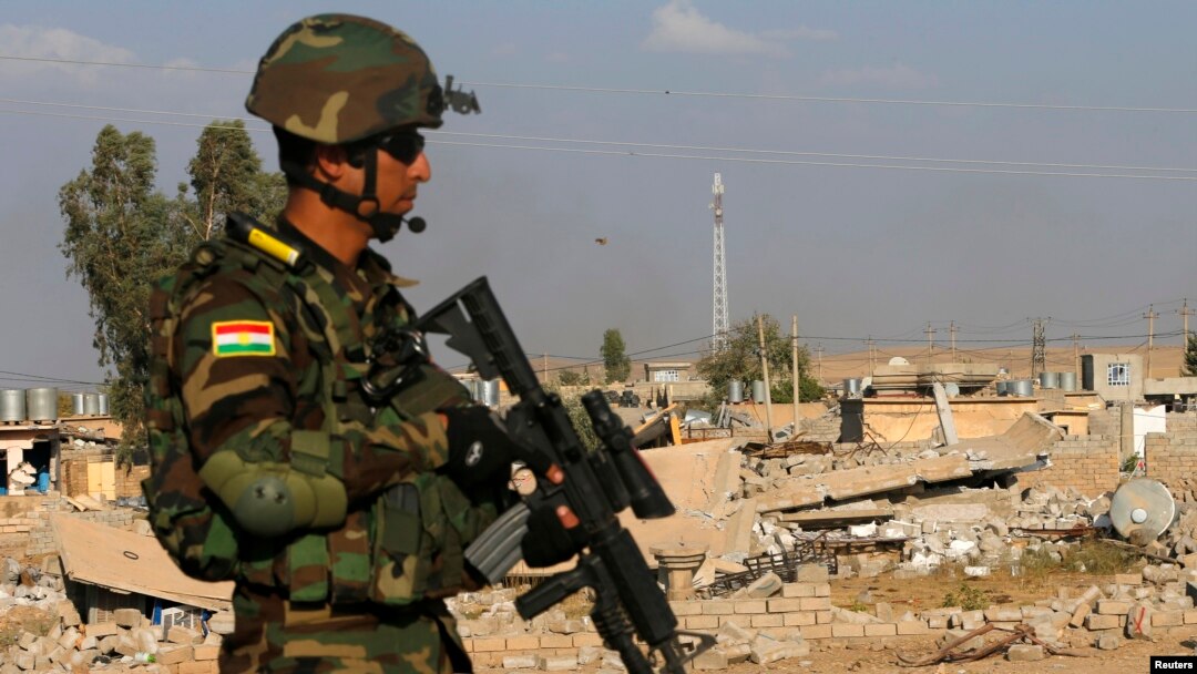 A Kurdish Peshmerga fighter walks past a house destroyed by American air strikes at Barznki village two days ago in Zummar, controlled by Islamic State (IS), near Mosul, Sept. 15, 2014. 
