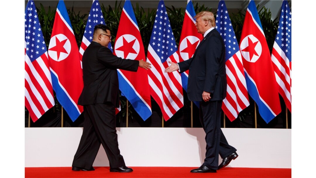 지난 2018년 6월 12일 싱가포르에서 열린 첫 미-북 정상회담에서 도널드 트럼프 미국 대통령과 김정은 북한 국무위원장이 악수를 하기 위해 서로에게 손을 내밀고 있다.