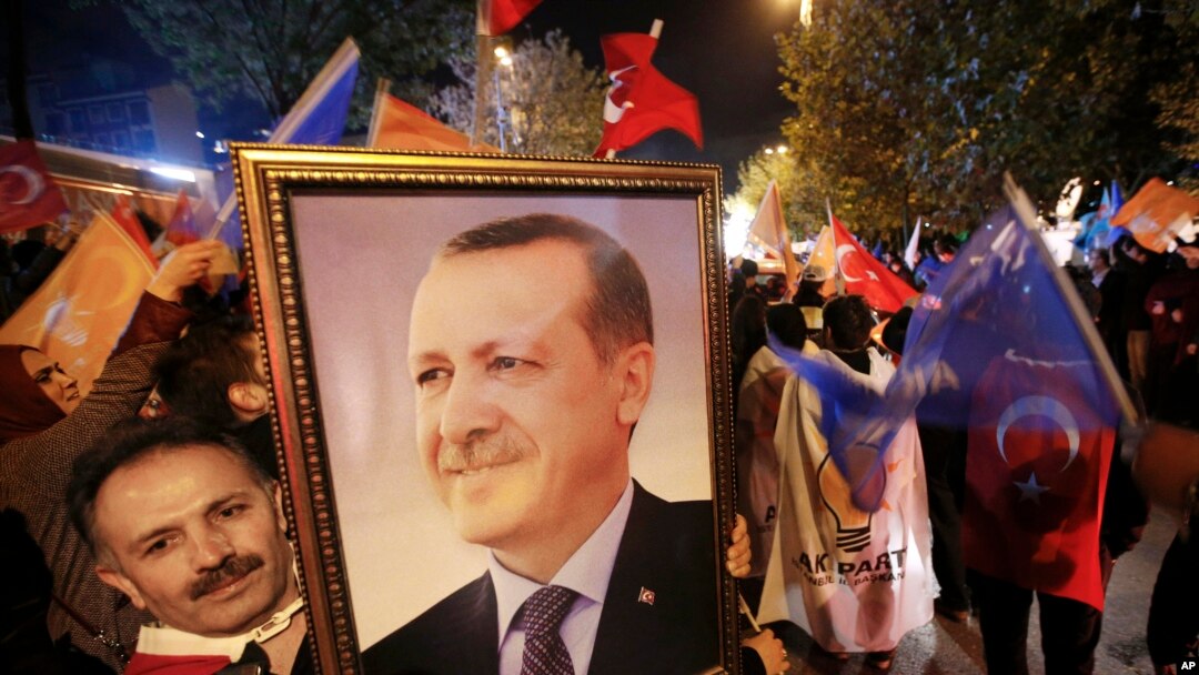 A supporter of the Justice and Development Party (AKP) holds a portrait of Turkey's President Recep Tayyip Erdogan at a celebration outside party headquarters in Istanbul, Turkey, Nov. 1, 2015.