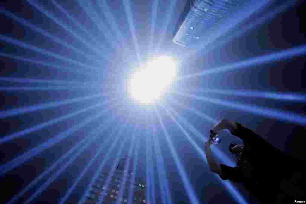 EMT with the Fire Department of New York and first responder Jason Butscher takes a photo of the Tribute In Light installation as it is illuminated over lower Manhattan marking the 17th anniversary of the 9/11 attacks in New York City, Sept. 11, 2018.