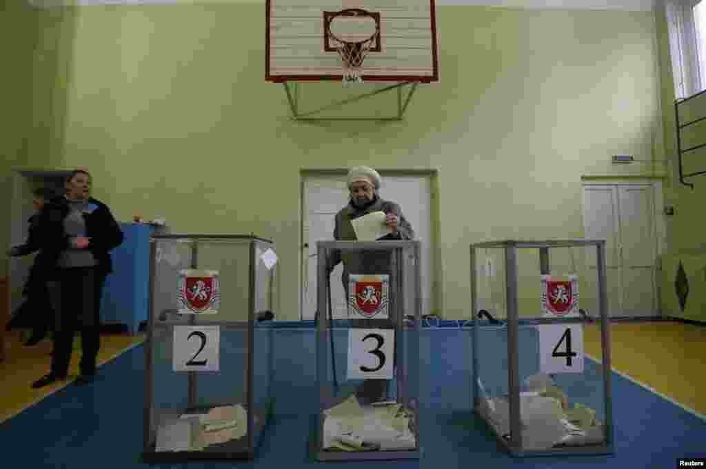 A woman casts her ballot during voting in a referendum at a polling station in Simferopol, Crimea, Ukraine, March 16, 2014.
