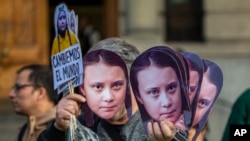FILE - A man sells Greta Thunberg masks during a climate protest rally in Santiago, Chile, Sept. 27, 2019.