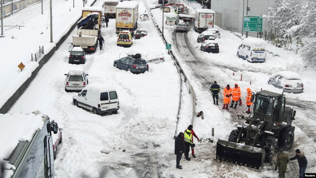 A Greek Army bulldozer plows snow next to abandoned vehicles following heavy snowfall, in Athens, Greece, Jan. 25, 2022.