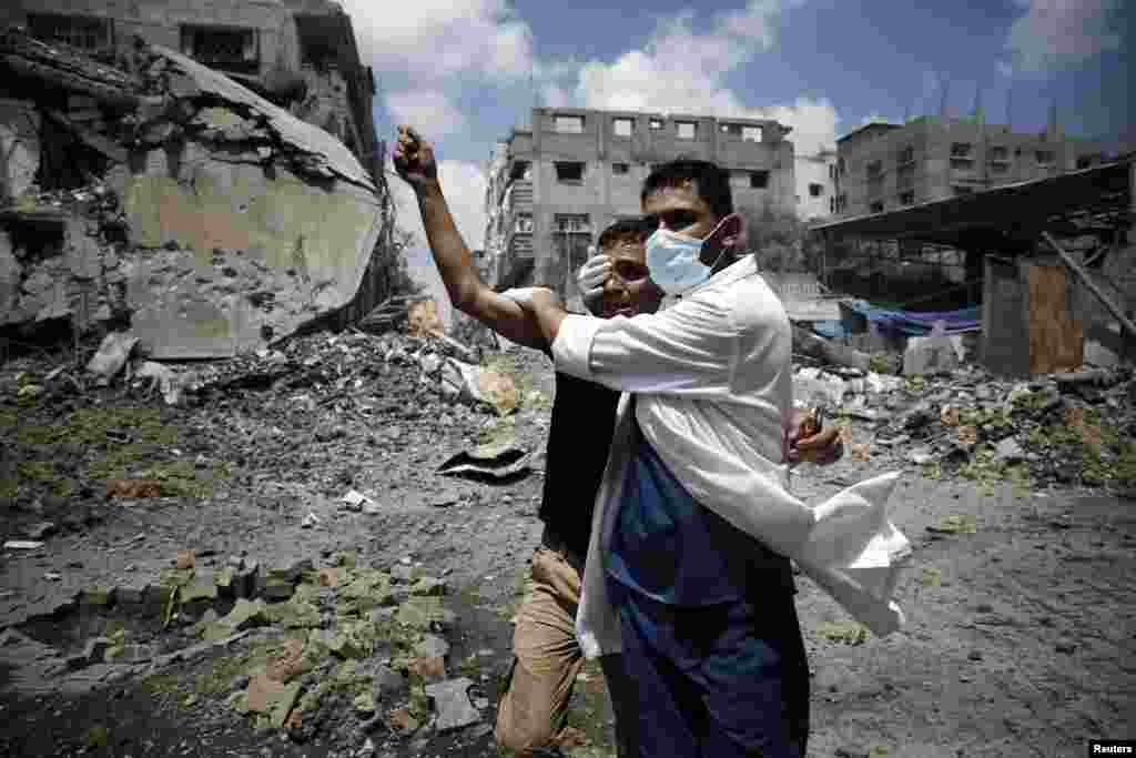 A medic helps a Palestinian in the Shejaia neighbourhood, which was heavily shelled by Israel during fighting, in Gaza City July 20, 2014.