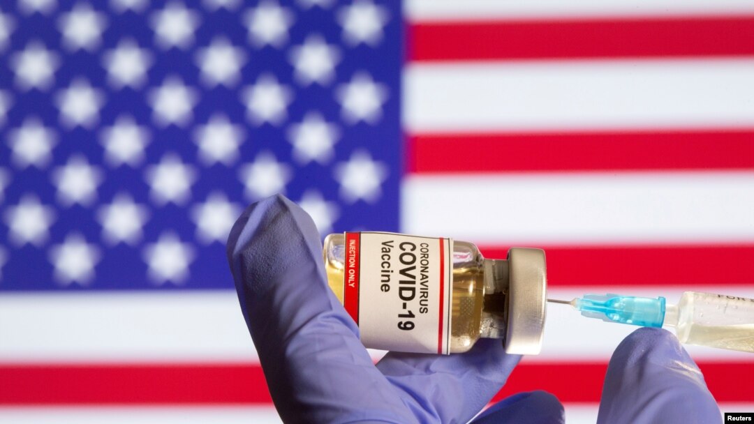 FILE - A woman holds a small bottle labeled with a "Coronavirus COVID-19 Vaccine" sticker and a medical syringe.
