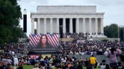Una pantalla gigante muestra un vídeo de la candidata demócrata a la vicepresidencia Kamala Harris, hablándole a los participantes de la marcha "Quita tu Rodilla de Nuestras Nucas".