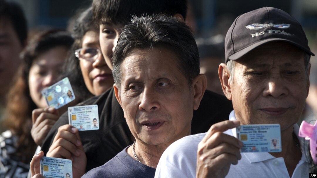 Thai voters show their ID cards as they queue to cast their ballot at a polling station in Bangkok on Feb. 2, 2014.