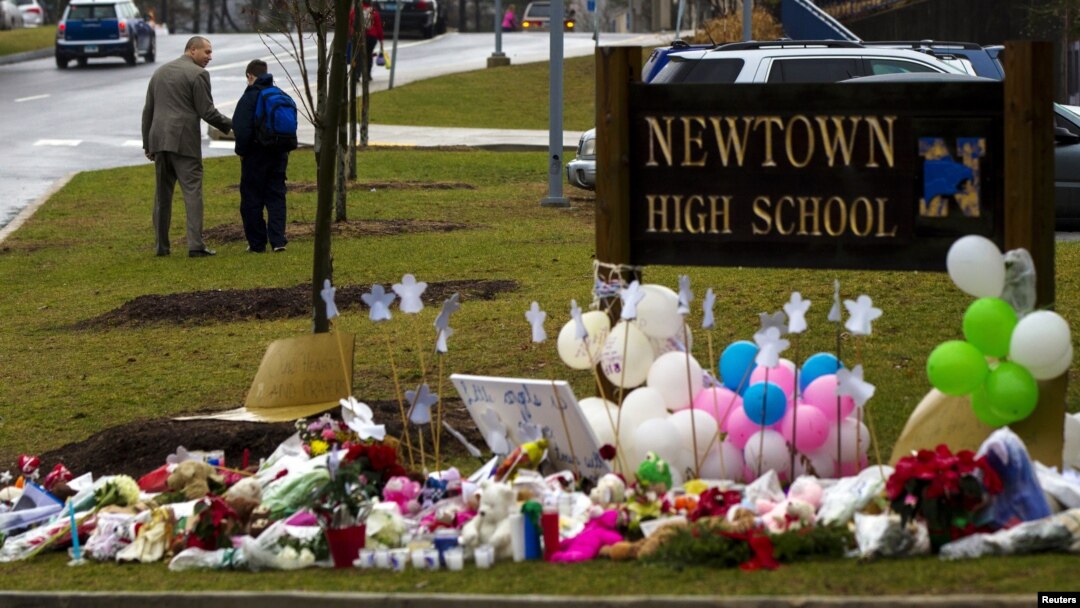 A student is consoled after he placed flowers on a memorial at the entrance to Newtown High School in Newtown, Connecticut December 18, 2012. 