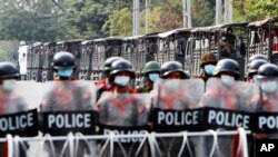 在緬甸曼德勒一處路障的緬甸警察和他們身後的軍車隊。(2022年2月19日)