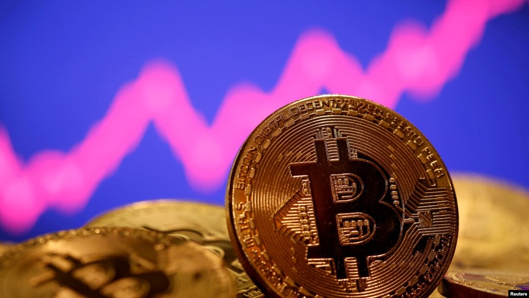 FILE - A representation of virtual currency bitcoin is seen in front of a stock graph in this photo illustration created Jan. 8, 2021. The value of bitcoin, the most popular form of cryptocurrency, has dropped more than 70% since its peak in November of last year.