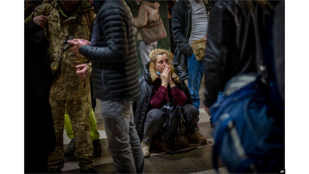 A woman reacts as she waits for a train trying to leave Kyiv, Ukraine, after Russian troops launched their anticipated attack on the country Feb. 24, 2022. (AP Photo/Emilio Morenatti)
