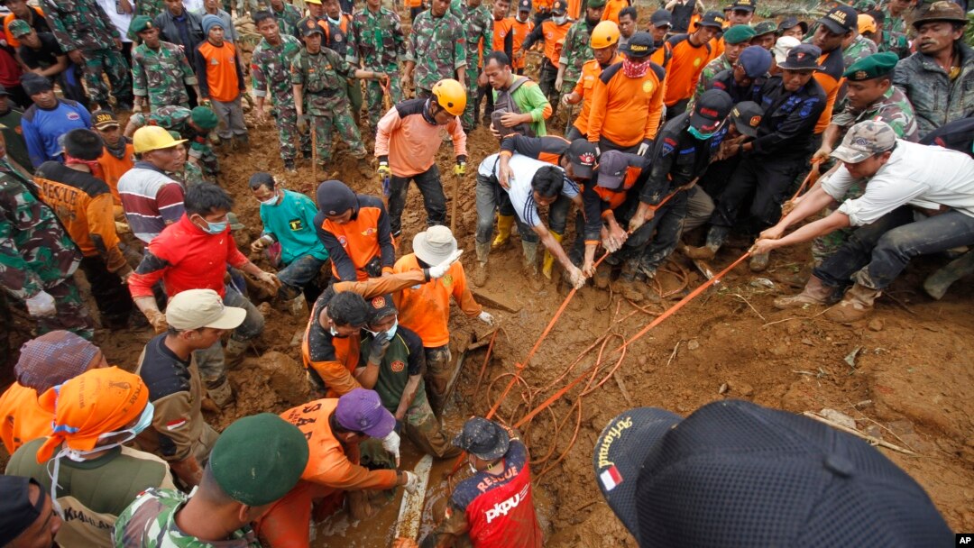 Recovery workers try to extricate the body of a victim of last week's landslide in Jemblung, Indonesia, Dec. 14, 2014