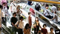 People wearing face masks to protect against the spread of the new coronavirus take an escalator at Yokohama station near Tokyo, July 22, 2020.