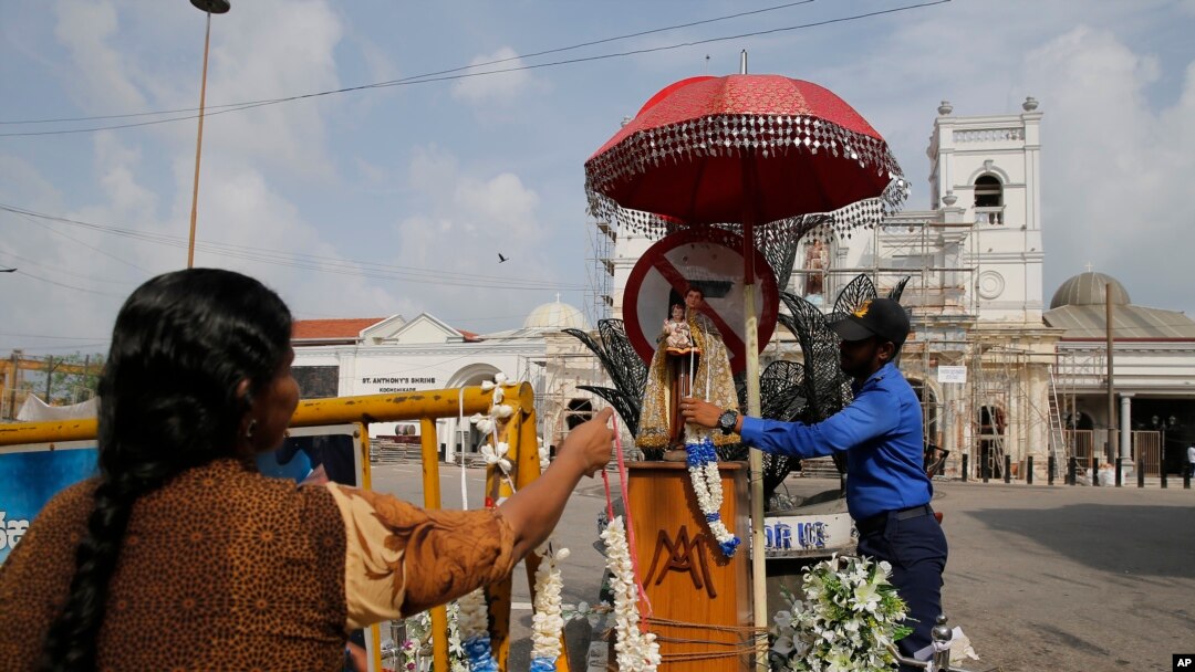A Sri Lankan navy officer helps a Catholic devotee offer a garland outside St. Anthony's Church, one of the targets of Easter Sunday attacks in Colombo, Sri Lanka, May 5, 2019. 
