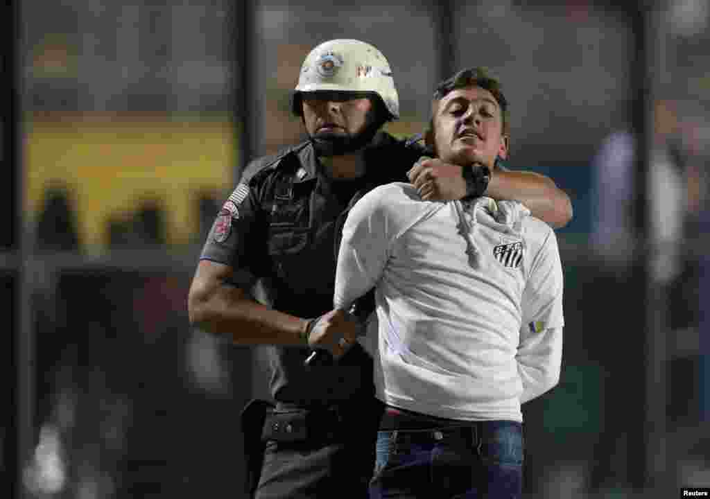 A police officer arrests a Santos soccer fan during their match against Independiente in Sao Paulo, Brazil,Aug. 28, 2018.