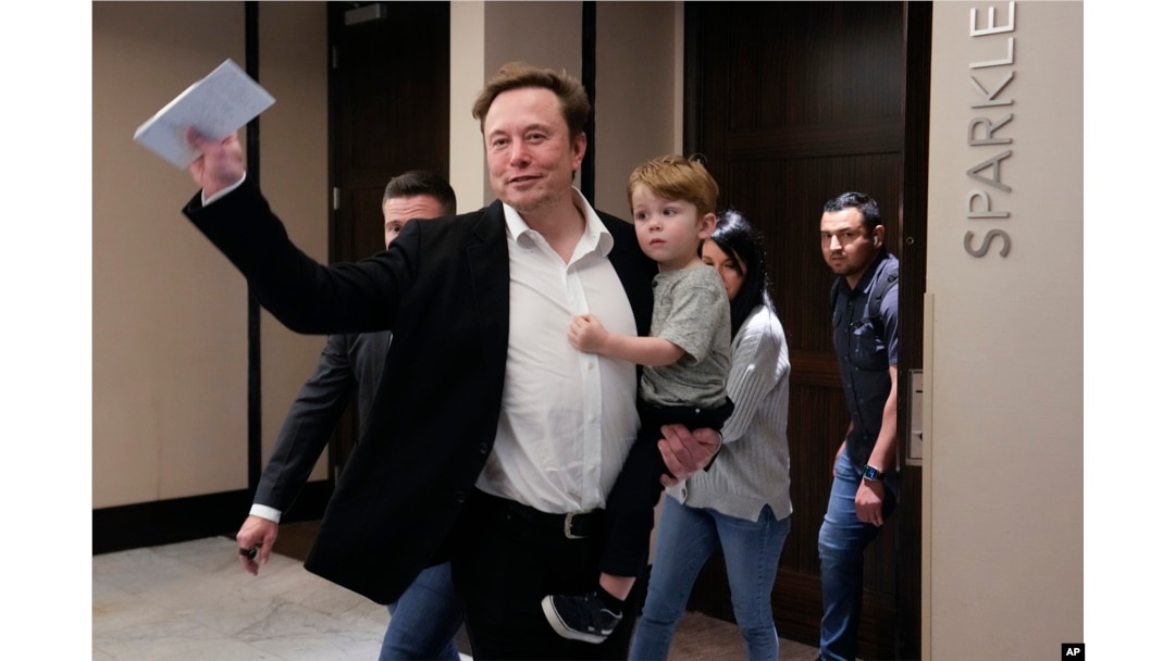 Twitter CEO Elon Musk waves as he leaves carrying his child after speaking at the POSSIBLE marketing conference, Tuesday, April 18, 2023, in Miami Beach, Fla. (AP Photo/Rebecca Blackwell)