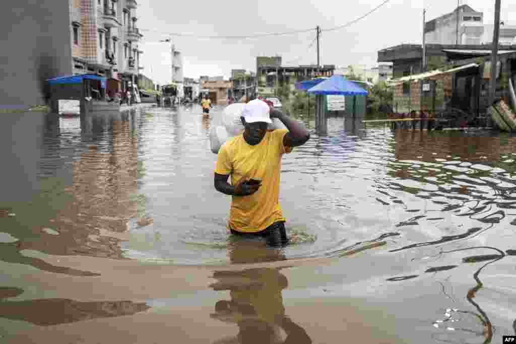 A man carries his belongings out of his house in the flooded neighbourhood of Keur Massar, Dakar.