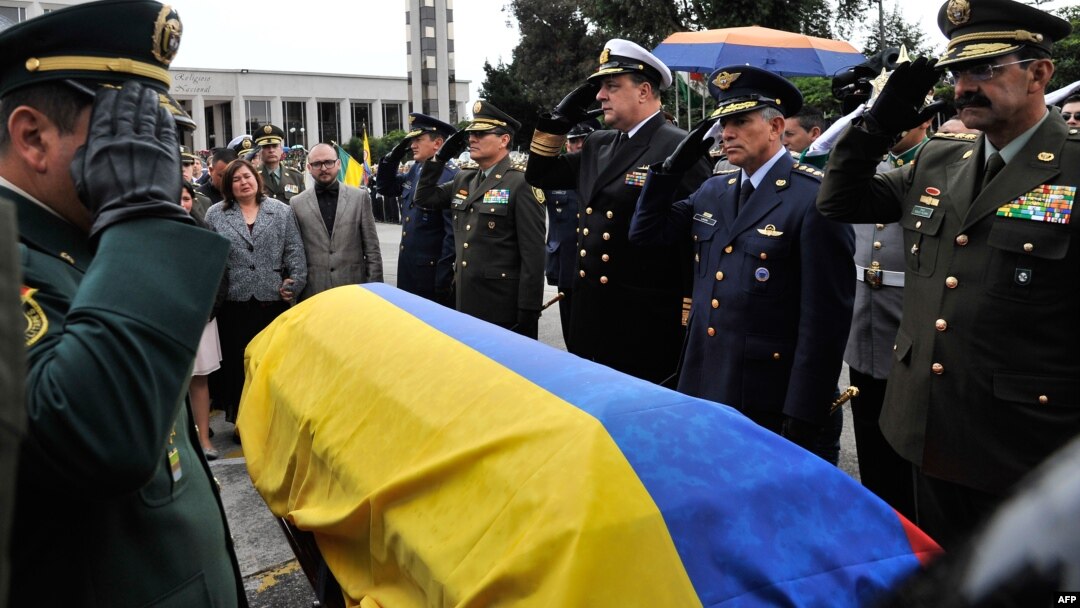 Commanders of the Police and Armed Forces of Colombia salute by the coffin of lieutenant colonel Alfredo Ruiz next to his wife Daissy Esperanza (2-L) during his funeral in Bogota, Colombia, on June 14, 2015. 