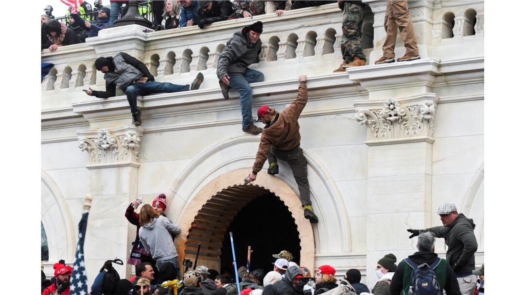Algunos manifestantes se encaraman a las paredes del Capitolio durante los disturbios.