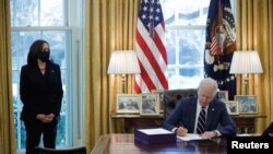 El presidente de EE.UU., Joe Biden, acompañado de la vicepresidenta Kamala Harris, firma el nuevo paquete de alivio por el coronavirus en la Casa Blanca, el 11 de marzo de 2021.
