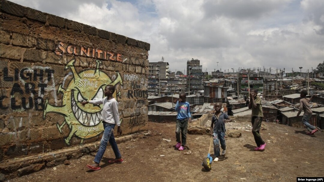 FILE - In this April 22, 2020, file photo, children walk past an informational mural depicting the coronavirus and warning people to sanitize to prevent its spread. (AP Photo/Brian Inganga, File)
