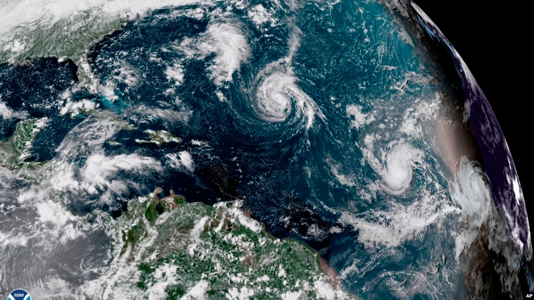 This enhanced satellite image made available by NOAA shows Tropical Storm Florence, center, in the Atlantic Ocean on Saturday, Sept. 8, 2018.