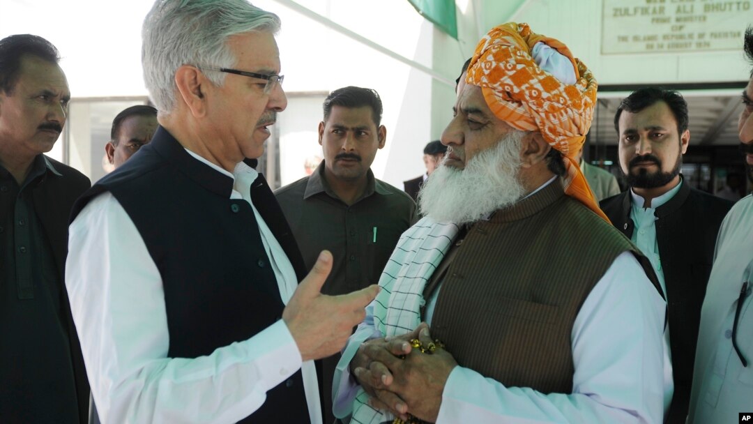 Pakistani Defense Minister Khawaja Muhammad Asif, left, confers with Jamat Ulema-e-Islam religious party leader Maulana Fazalur Rehman outside Parliament in Islamabad, April 10, 2015. Legislators decided not to join the Saudi-led coalition.