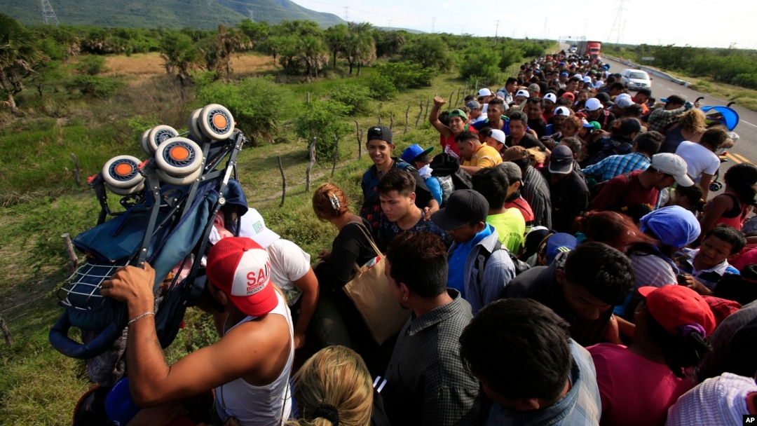 A man holds up a stroller as hundreds of migrants hitching a ride accommodate themselves on the back of truck, between Niltepec and Juchitan, Mexico, Oct. 30, 2018.