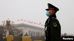 FILE - A paramilitary police officer stands guard near the Great Hall of the People before the opening session of the National People's Congress (NPC) in Beijing, March 5, 2021. 