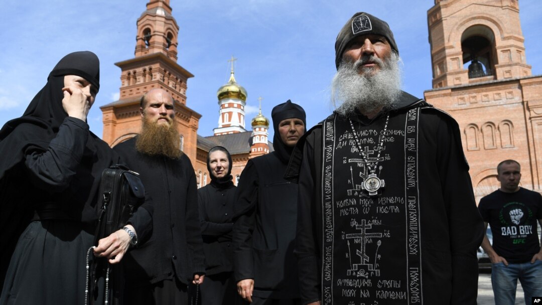 Father Sergiy, a Russian monk who has defied the Russian Orthodox Church's leadership, right, speaks with journalists in Sredneuralsk, Russia, June 17, 2020. 