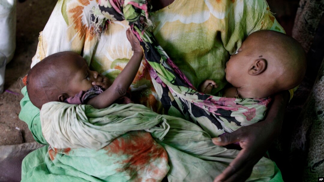 FILE - A Somali refugee cradles her one-month old twins, born at the camp hospital, as she sits on the sand floor of a makeshift shelter in Hagadera Camp, outside Dadaab, Kenya, July 9, 2011. A new study has found that 1 in 5 twins born in sub-Saharan Africa dies before the age of 5.